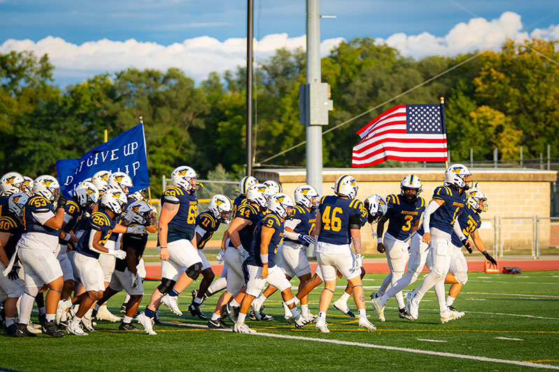 Football players running on the field. Links to Gifts by Will