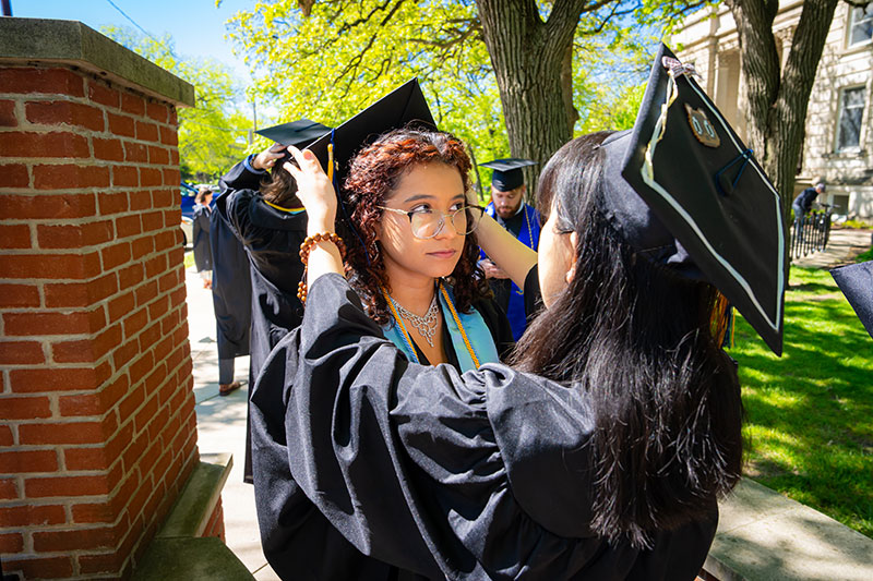 A girl helping another girl with her graduation cap. Links to Gifts of Life Insurance A girl helping another girl with her graduation cap. Links to Gifts of Life Insurance
